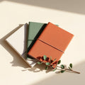 Three linen-wrapped gratitude notebooks in ivory, sage and rust