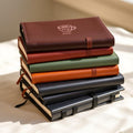 Stack of vegan leather teacher journals in espresso, rust, sage and black
